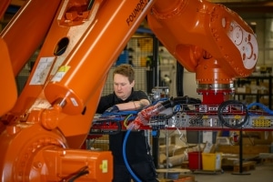 man som arbetar med en orange stor industrirobot